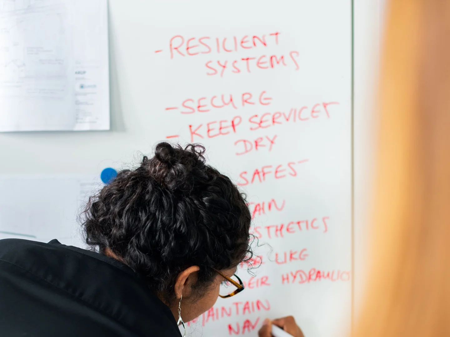 Engineer documenting resilient systems and security considerations on a planning whiteboard