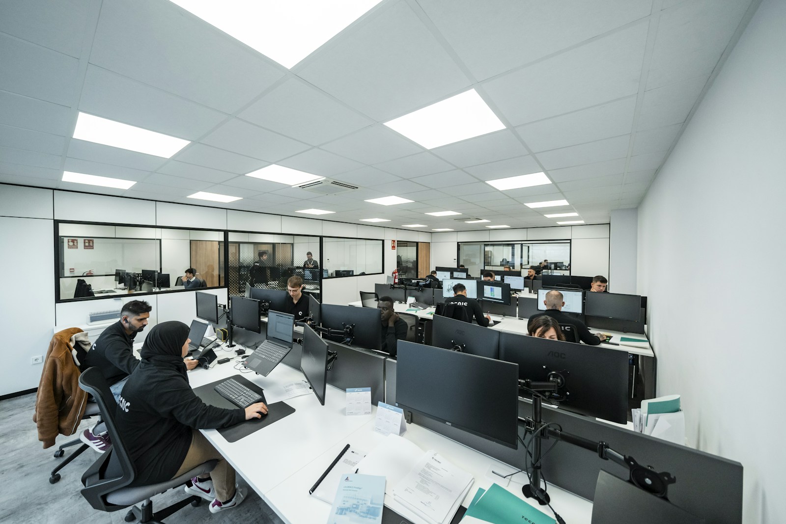 Professionals working at desktop monitors in an open-plan technology office