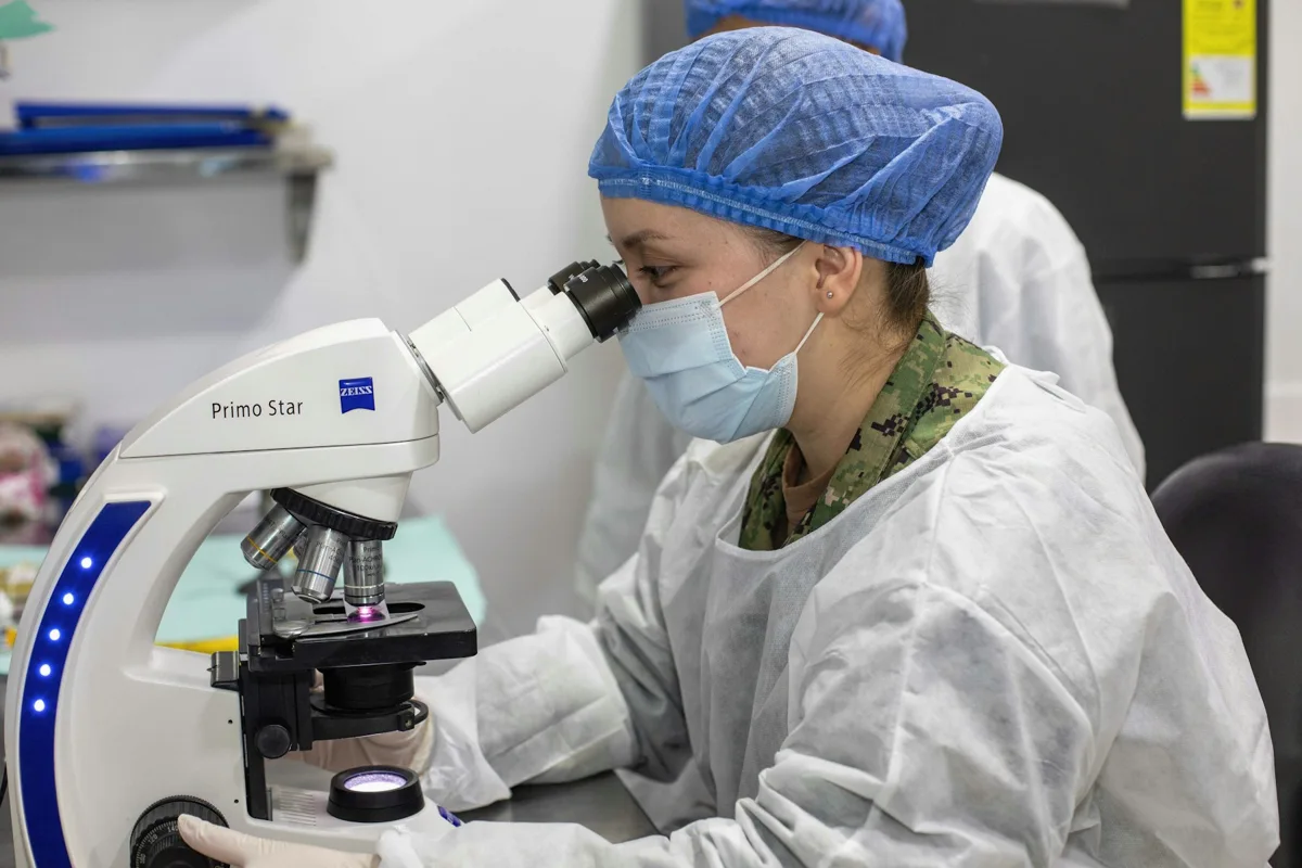 Laboratory technician examining a specimen through a microscope